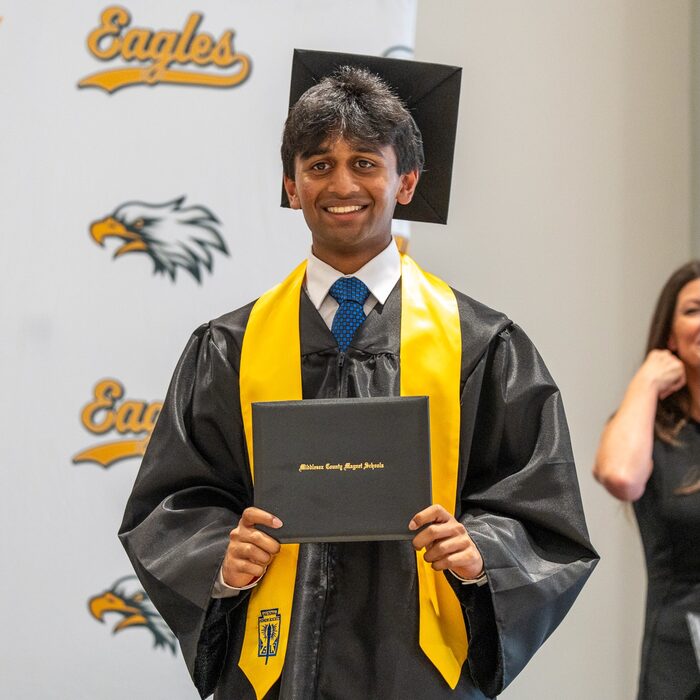 Abhi holding his high school diploma at graduation