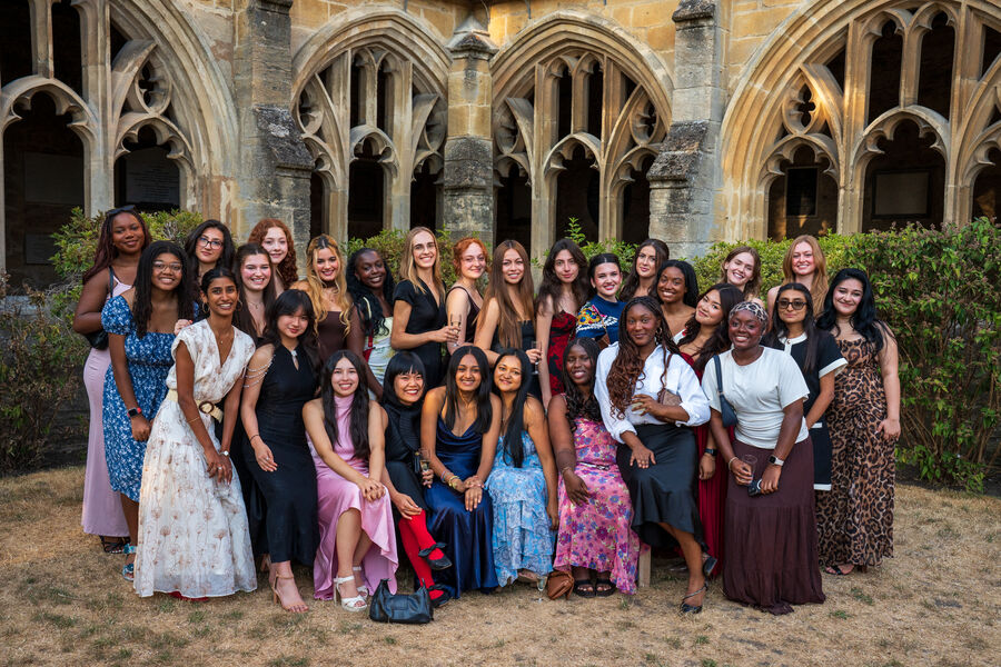 A large group in formal dress in the cloister of New College, Oxford
