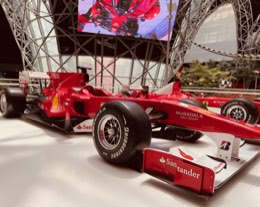 A red Formula 1 Ferrari on display beneath a glass dome